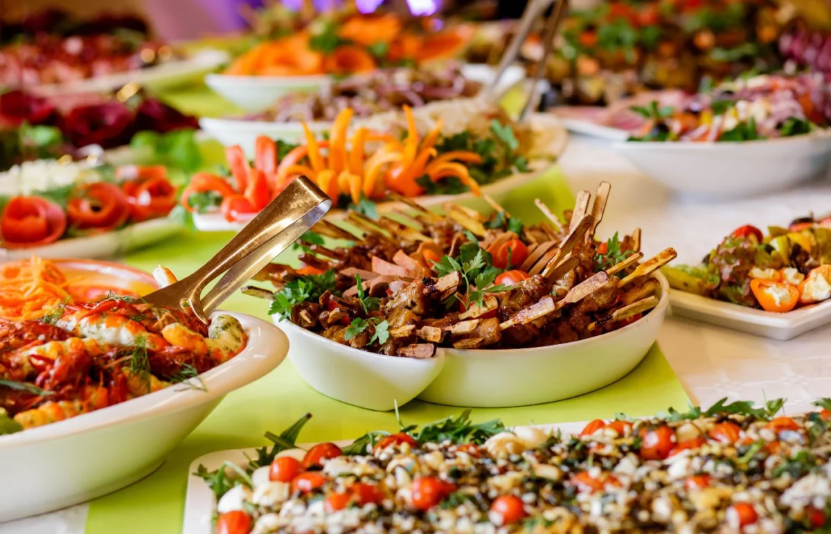 Buffet gourmet avec une variété de plats colorés et créatifs, incluant viandes grillées, légumes et salades, parfait pour une réception élégante.