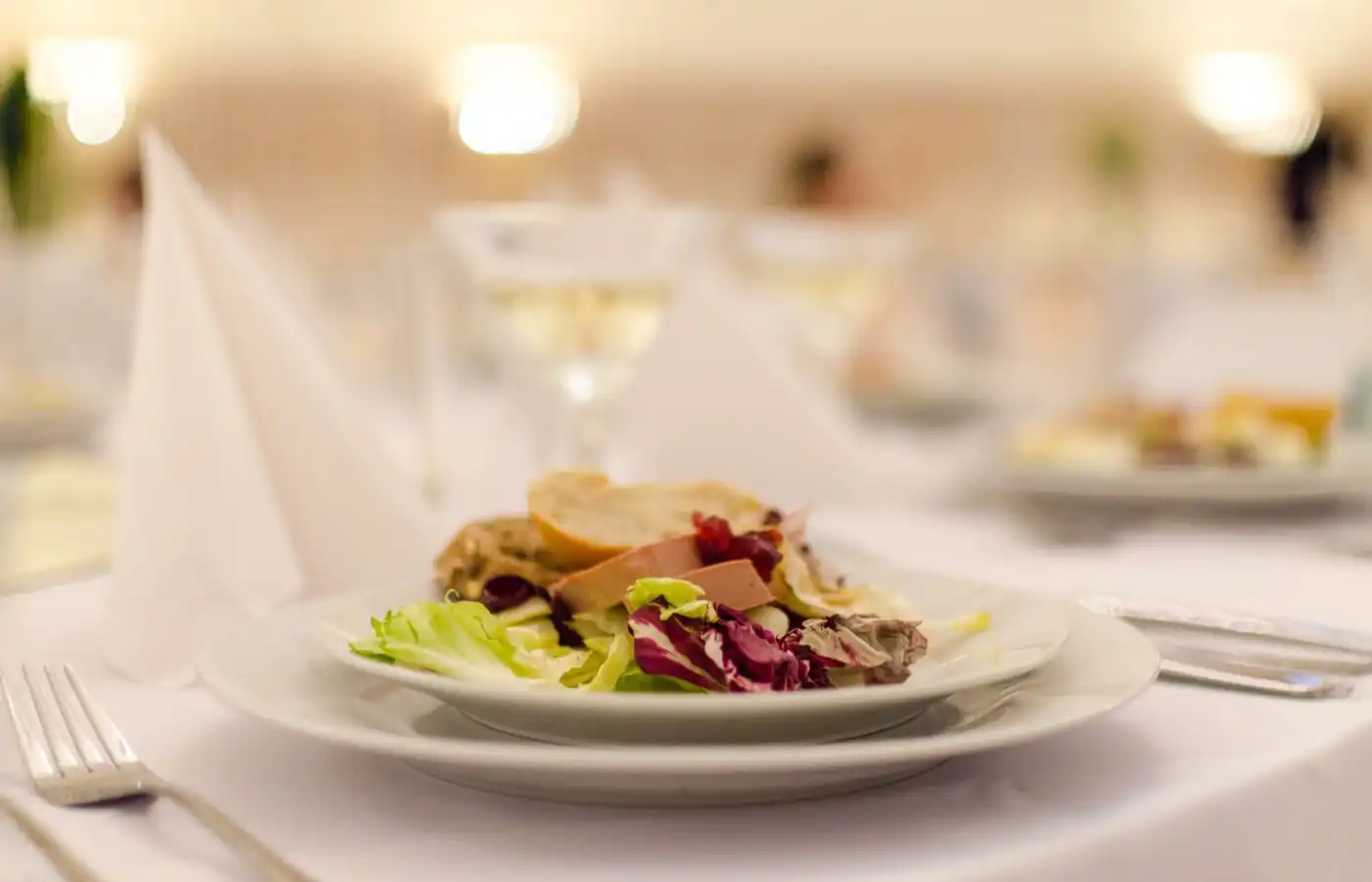 Assiette élégante de salade gourmande avec foie gras et pain, illustrant la finesse et le raffinement des menus de réception.