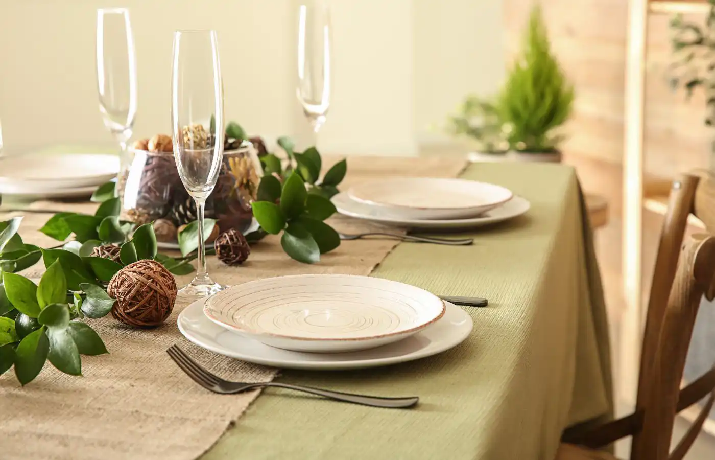 Table dressée avec vaisselle en céramique, décoration en feuillages et détails naturels, créant une ambiance élégante et naturelle.