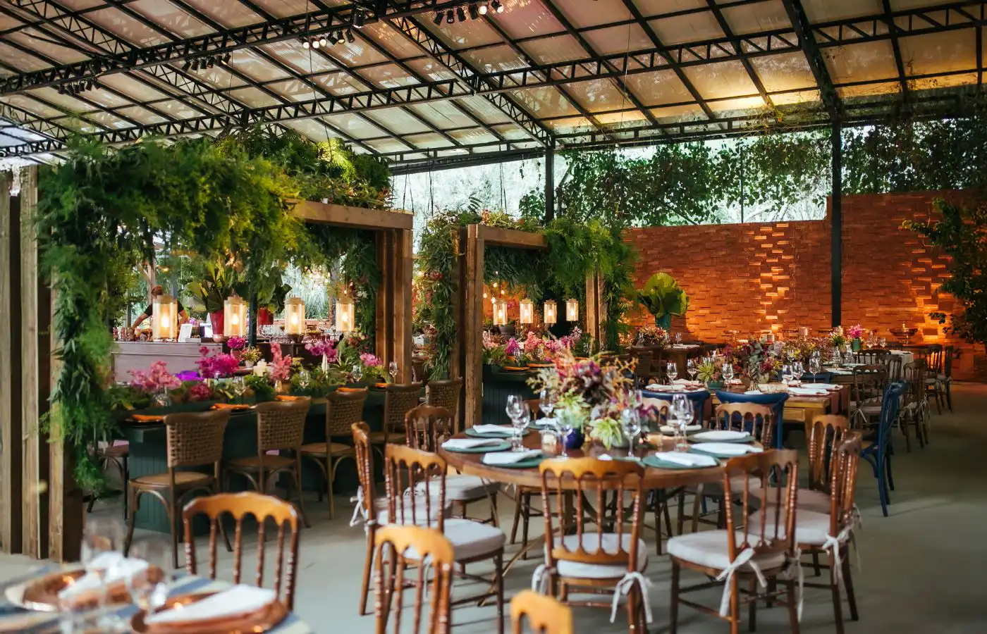 Cadre de réception élégant avec tables décorées de fleurs et de verdure dans un espace couvert, créant une ambiance haut de gamme et naturelle.